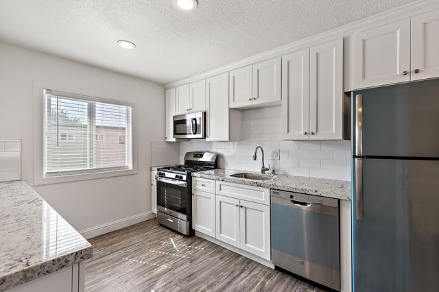 Bright kitchen with modern stainless steel appliances, sleek granite countertops, and elegant white cabinetry.