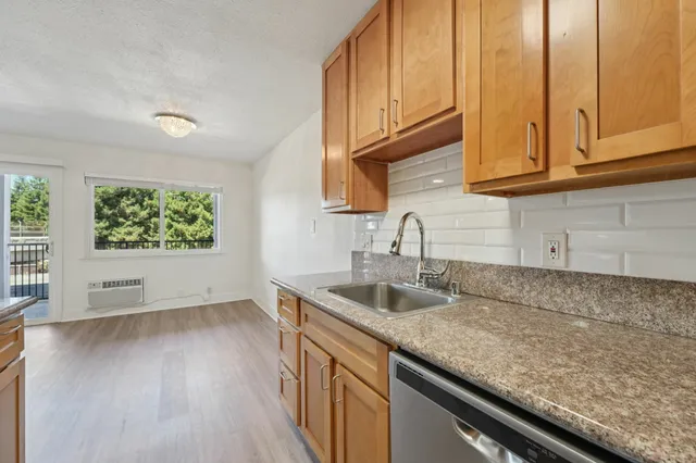 Bright kitchen area with modern wooden cabinetry, sleek granite countertops, and a large window offering scenic views and natural light.