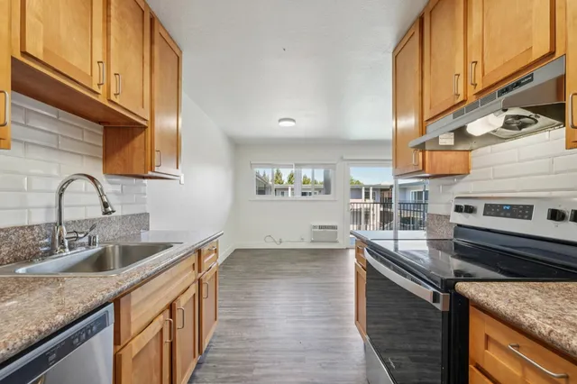 Bright kitchen with sleek granite countertops, modern appliances, and natural wood cabinets offering a welcoming atmosphere.