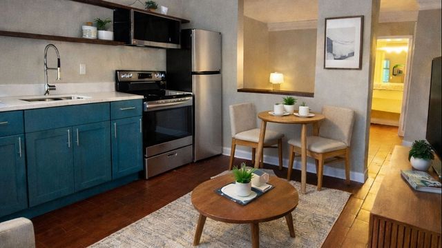 Charming apartment interior featuring an open kitchen with vibrant cabinetry, cozy dining area, and modern living space with warm wooden flooring.