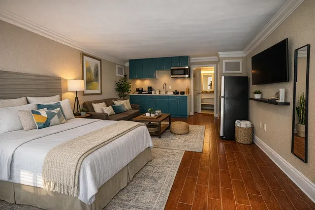 Chic studio apartment with modern amenities, featuring a cozy bed, stylish kitchenette with teal cabinets, and comfy living area.