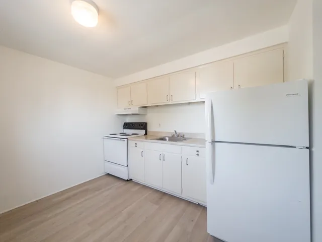 kitchen with refrigerator and range included, cabinets and sink with stone counter