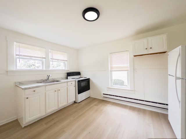 Bright, modern kitchen with sleek white cabinetry, spacious countertop, and large windows offering natural light.