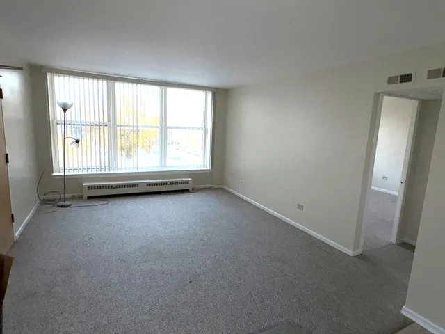 Living room looking at 3 large windows fully carpeted