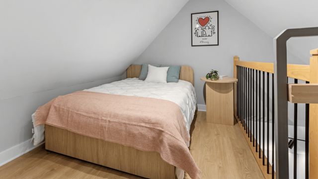 Charming attic bedroom with a cozy double bed, a wooden bedside table, and stylish decor, offering a serene and inviting atmosphere.