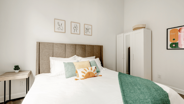 Stylish bedroom with a cozy king-sized bed, modern art decor, and a sleek wardrobe, perfect for a serene retreat.