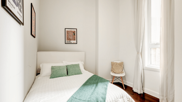 Cozy bedroom with modern decor, featuring a comfortable bed, stylish artwork, and a bright window with elegant curtains.
