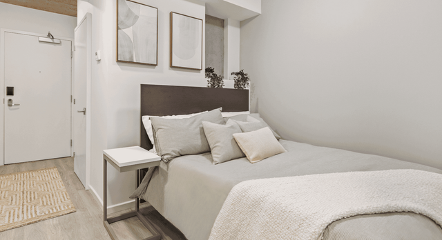 Inviting bedroom with modern decor, featuring a plush bed, cozy blankets, and minimalist artwork on the wall.