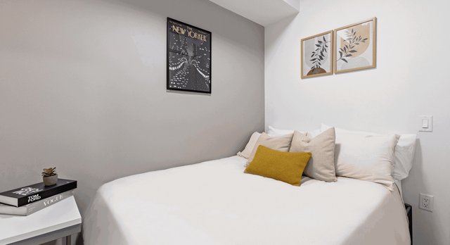 Cozy modern bedroom featuring stylish decor, soft pillows, and elegant art prints.