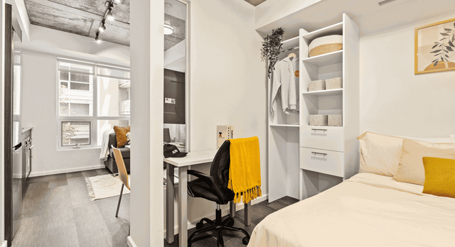 Modern studio apartment featuring a cozy bedroom with open shelving, a stylish workspace, and abundant natural light.