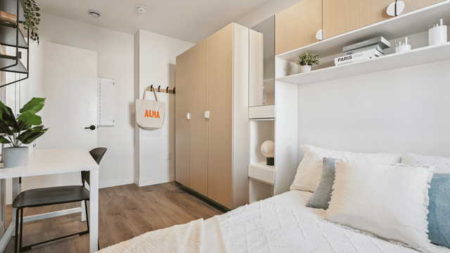 Bright and modern bedroom with sleek storage, elegant decor, and a cozy workspace.