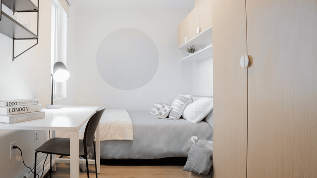 Cozy bedroom featuring modern decor, a comfortable bed, and a sleek workspace with ample natural light.