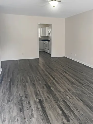 Spacious living area with modern dark wood flooring leading to a sleek kitchen, perfect for family gatherings.