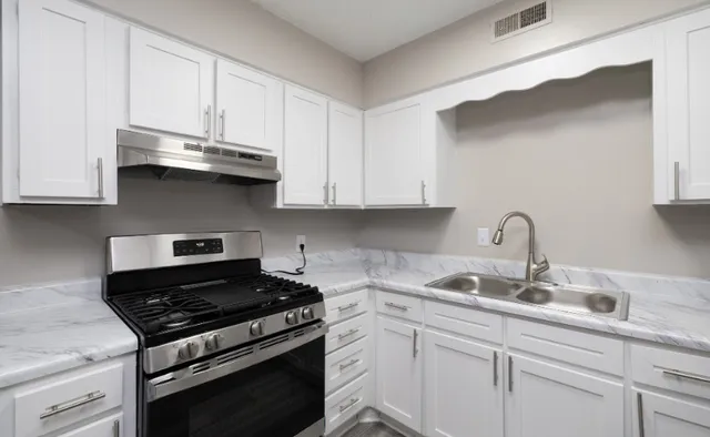 Modern kitchen with sleek white cabinetry, stainless steel appliances, and elegant marble countertops.