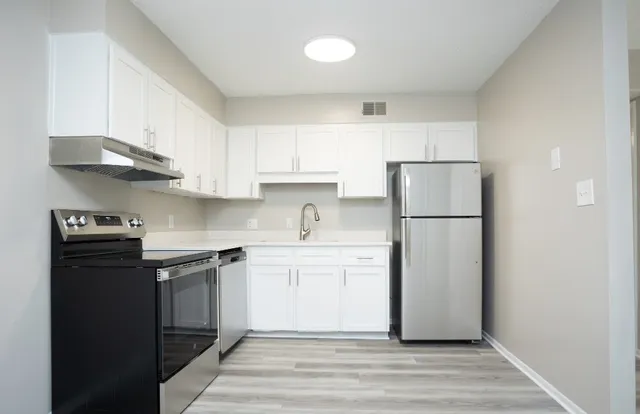Contemporary kitchen featuring sleek stainless steel appliances, white cabinetry, and modern lighting.