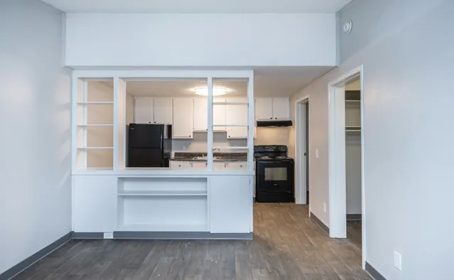 Modern open kitchen view with sleek cabinets, spacious countertops, and a large black refrigerator. Bright and inviting atmosphere with ample storage and natural light.