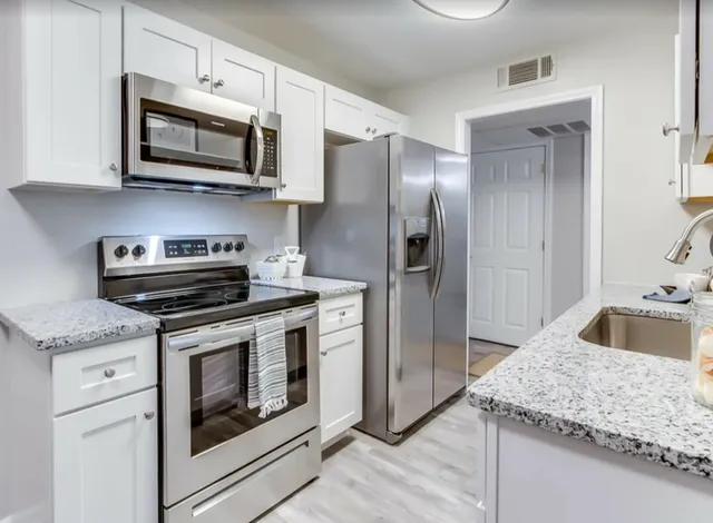 Modern kitchen with sleek stainless steel appliances, elegant granite countertops, and pristine white cabinetry.