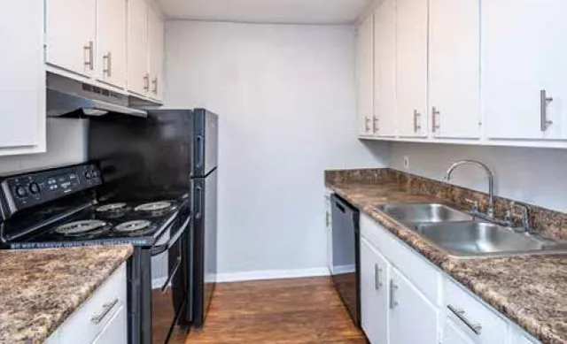Modern kitchen with sleek black appliances, marble countertops, and ample cabinetry for storage.