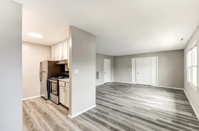 Bright, modern living space with sleek hardwood floors and a compact kitchen featuring stainless steel appliances.