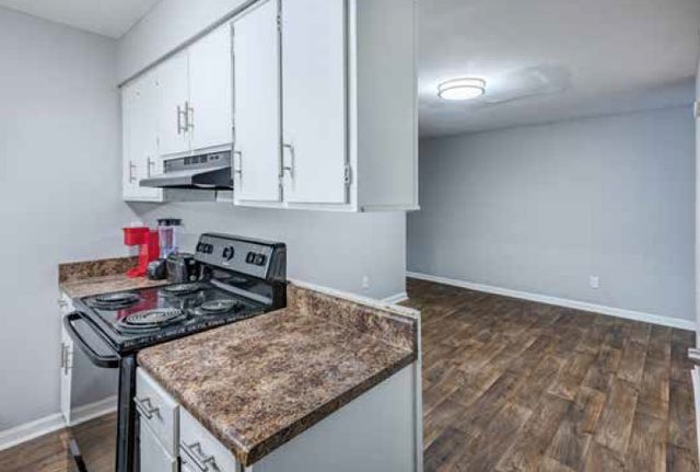Modern kitchen with sleek countertops, stylish cabinetry, and open layout leading to a spacious living area featuring elegant hardwood floors.