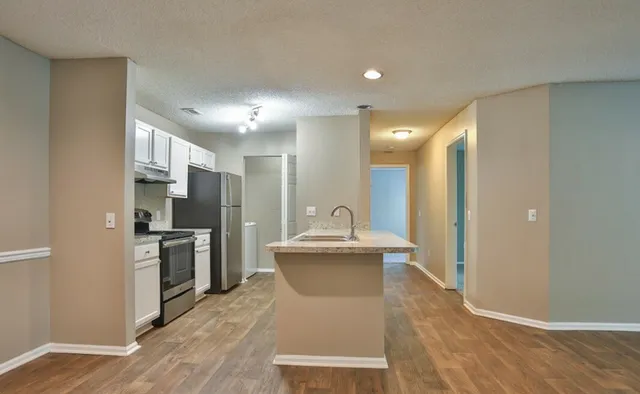 Modern kitchen with sleek stainless steel appliances, spacious island counter, and elegant wooden flooring.