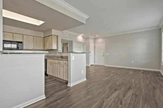 Spacious open-concept living area showcasing modern kitchen with sleek countertops and ample cabinetry, complemented by elegant wood flooring.