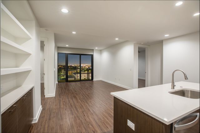 Elegant open-concept apartment with modern kitchen, hardwood floors, and city view balcony access.