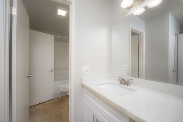 Bright and modern bathroom with sleek white vanity, spacious mirror, and elegant lighting.