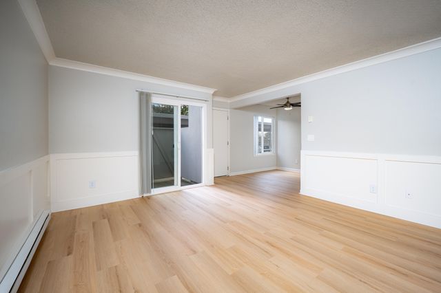 Bright and spacious living area with elegant wood flooring, sliding glass doors, and modern ceiling fan, perfect for a contemporary lifestyle.