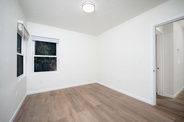 Bright and airy room with hardwood floors and a large window, showcasing a modern and clean design.