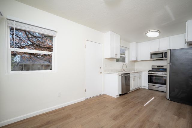 Bright modern kitchen featuring stainless steel appliances, sleek white cabinets, and large window view.