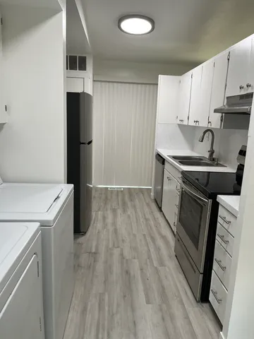 Contemporary kitchen with sleek stainless-steel appliances, modern cabinetry, and elegant wood flooring, perfect for culinary enthusiasts.