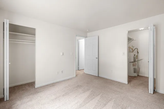 Bright and spacious bedroom with plush carpet, open closet space, and neutral walls for a modern touch.