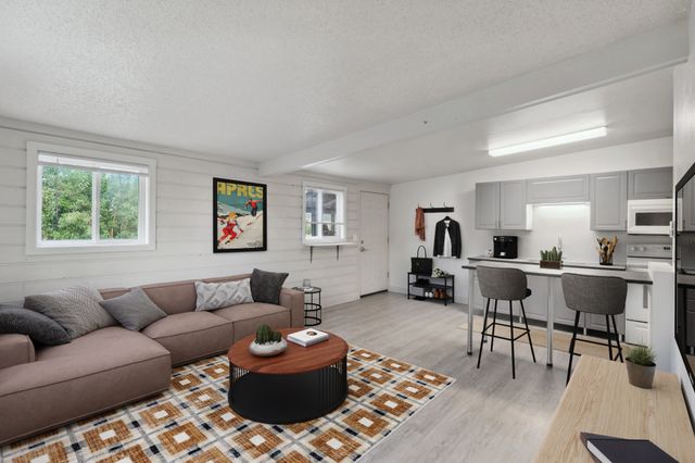 Charming open-concept living room and kitchen with cozy seating, stylish decor, and modern appliances.