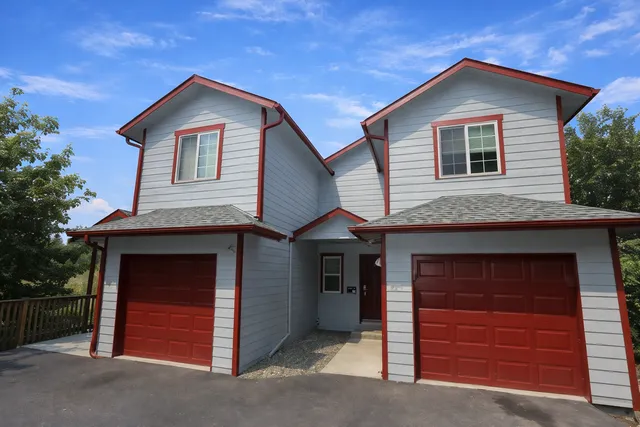 Coug Housing two-story house with twin garages, red trim accents, and a welcoming driveway.