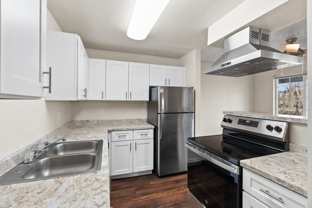 Contemporary kitchen with white cabinets, stainless steel appliances, and granite countertops.