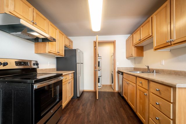 Elegant kitchen with stainless steel appliances, wooden cabinetry, and dark wood flooring.
