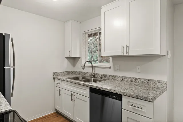 Modern kitchen with sleek white cabinets, granite countertops, and stainless steel appliances.