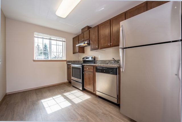 Modern kitchen featuring stainless steel appliances, wooden cabinetry, and natural lighting from a large window.