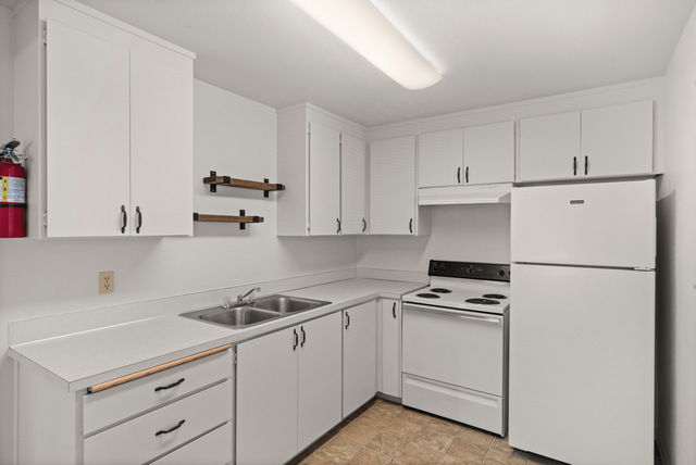 Bright, modern kitchen with sleek white cabinets, electric stove, and ample storage space.