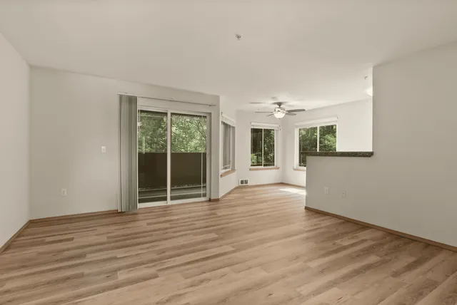 Bright and spacious open-concept living area with elegant hardwood flooring, large windows, and a cozy balcony view.