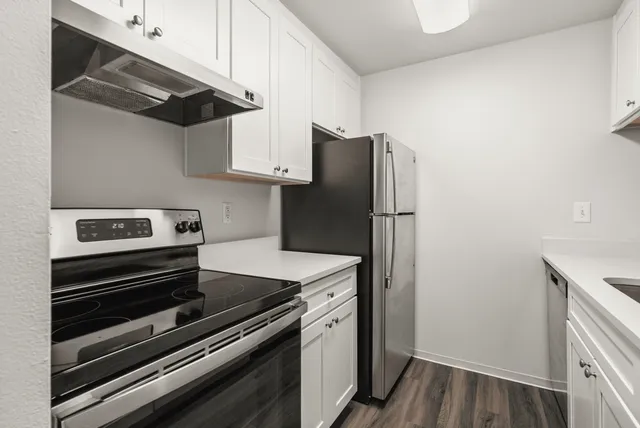 Modern kitchen with sleek stainless steel appliances, elegant white cabinetry, and beautiful wood flooring.