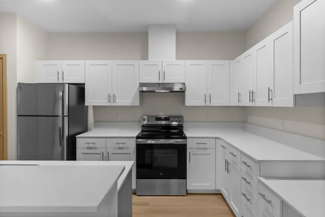 Modern kitchen with sleek stainless steel appliances, bright white cabinetry, and ample counter space.