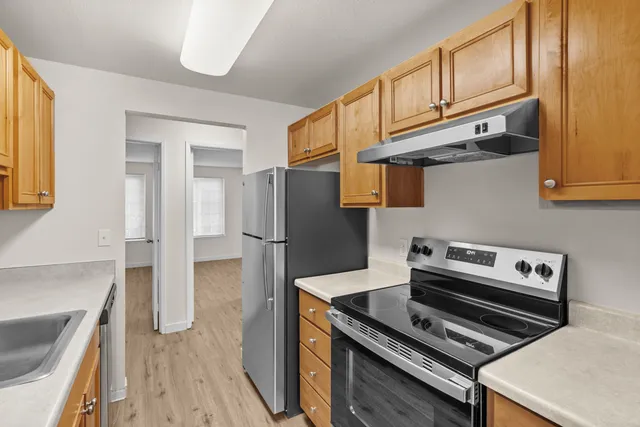 Modern kitchen with stainless steel appliances, sleek countertops, and warm wooden cabinetry.