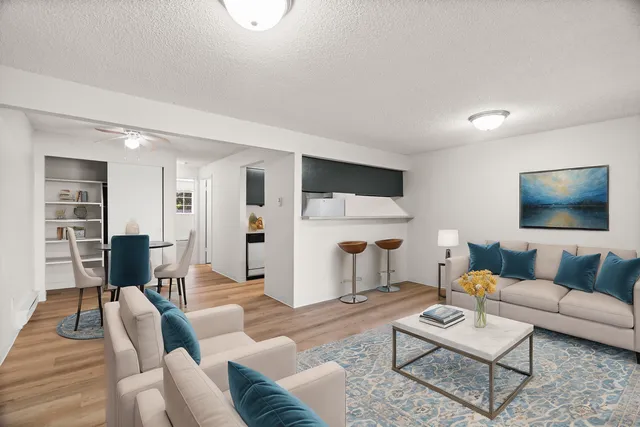 Bright and modern living room with cozy beige seating, stylish blue accents, an elegant dining area, and a charming breakfast bar.