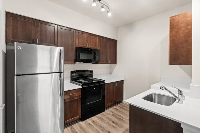 Modern kitchen with sleek stainless steel appliances, elegant cabinetry, and polished countertops in a spacious apartment.