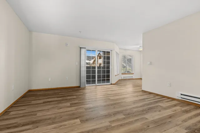 Bright and spacious living area with elegant wood flooring, large windows, and sliding glass doors opening to a beautiful view.