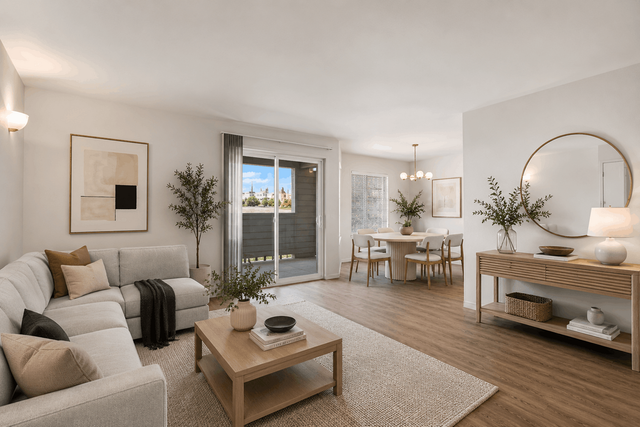 Bright and modern living-dining area with a cozy sofa, elegant wood furnishings, and ample natural light from sliding glass doors.