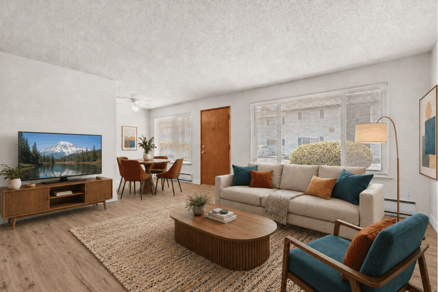 Inviting living room with a large window, stylish sofa, modern armchair, and cozy dining area. Natural light fills the space, highlighting the elegant decor and wooden furnishings.
