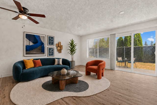 Elegant living room with plush blue and orange seating, modern art, and large windows overlooking a relaxing patio.